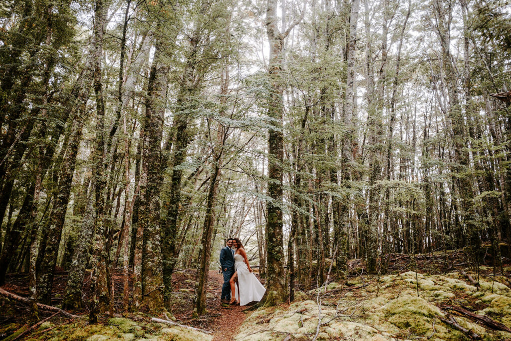 bride and groom kissing under trees in a forest in glenorchy new zealand