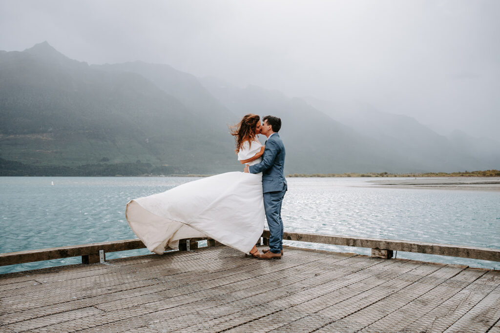 bride and groom kissing at a wharf in glenorchy new zealand
