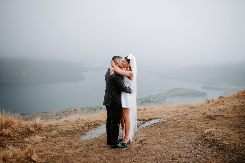 bride and groom kissing in the rain after elopement