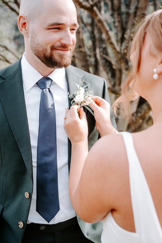 bride pinning boutonnière to groom