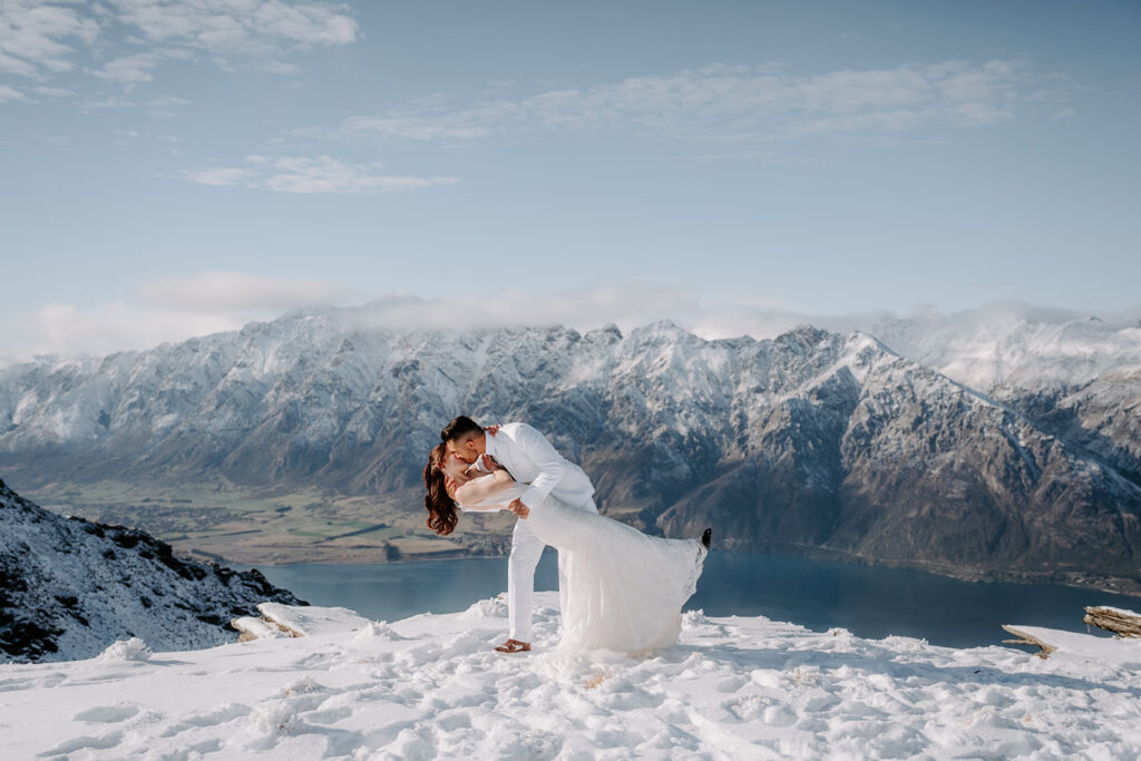 bride and groom kissing on top of cecil peak for their snowy elopement in queenstown